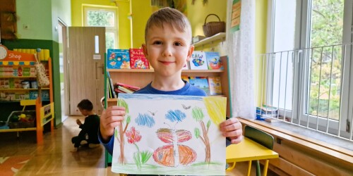 Chłopiec Maks trzyma rysunek motyla.