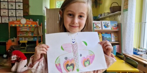 Dziewczynka Maja trzyma rysunek motyla.